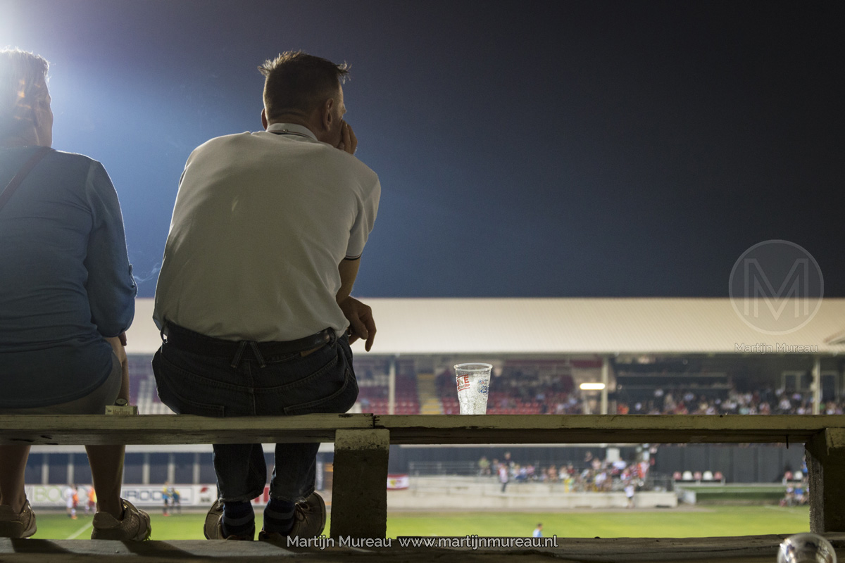 Een fan van Royal Antwerp FC kijkt -met zijn biertje naast zich- aandachtig naar de wedstrijd